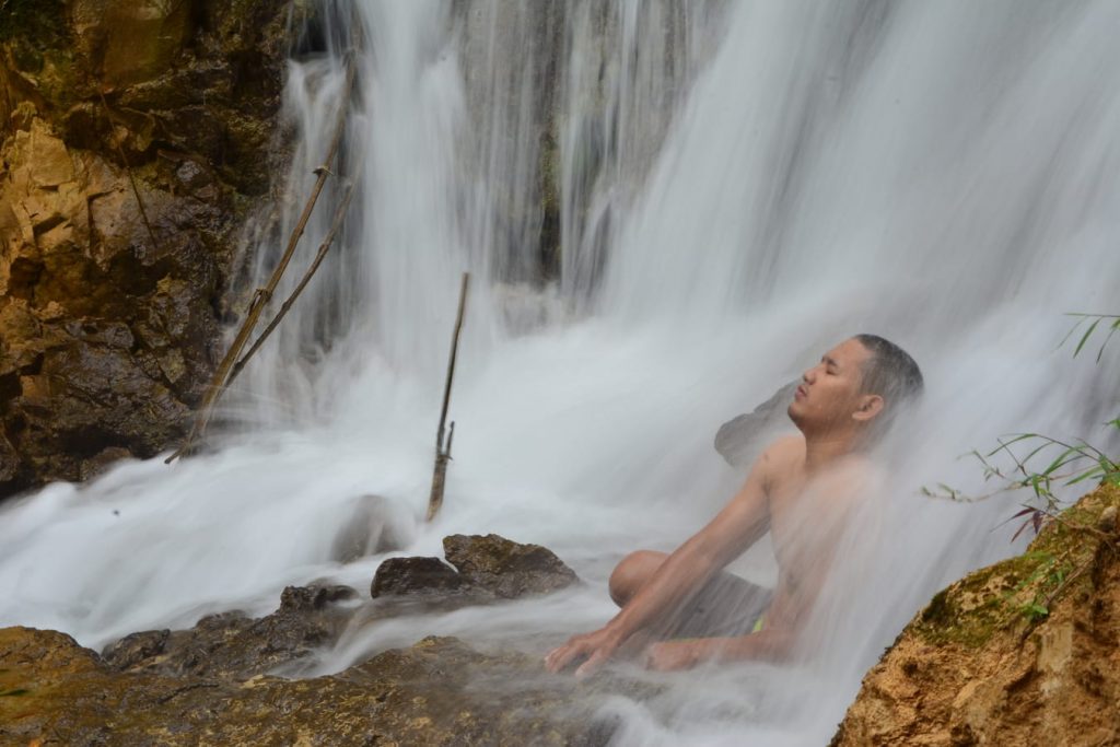 Wodospad Yogyakarta mezczyzna siedzacy pod wodospadem zen